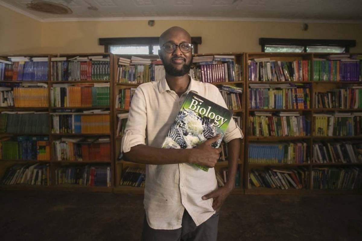 This handout picture shows Abdullahi Mire posing for a picture in one of the libraries he established in Kenya’s Dadaab refugee camp.