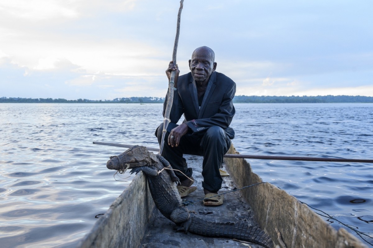 Legendary hunter Papa Baron Missiki, 91, poses for a photo with a crocodile and his spear on a pirogue on the Congo River in DR Congo.--AFP photos