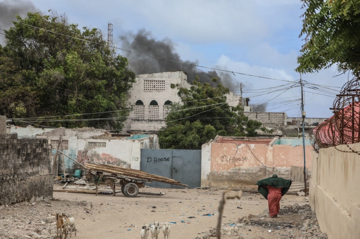 MOGADISHU: A woman reacts while walking in a street as smoke billows in the background after an explosion in Mogadishu. – AFP