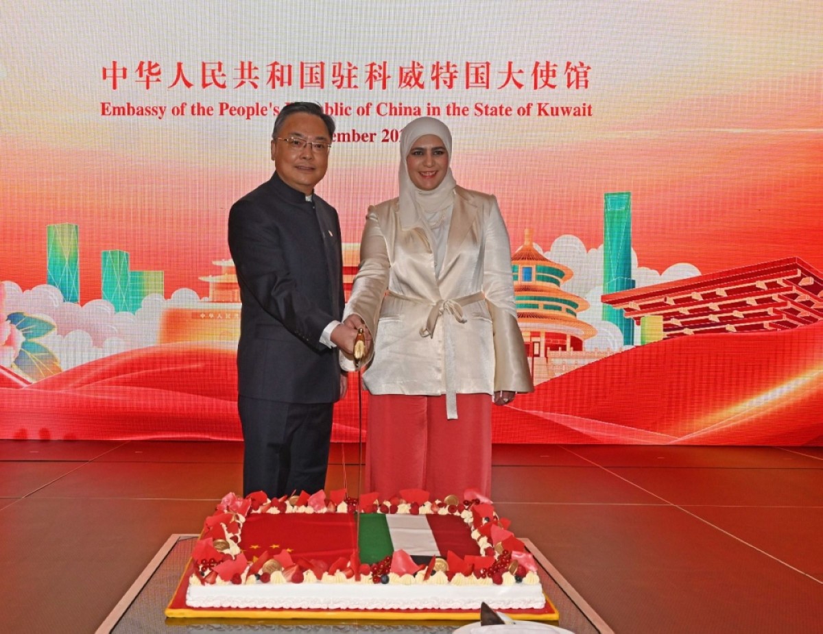 Chinese Ambassador Zhang Jianwei (left) and Minister of Finance in Kuwait Noura Al-Fassam (right) celebrating by cutting the cake at the event.