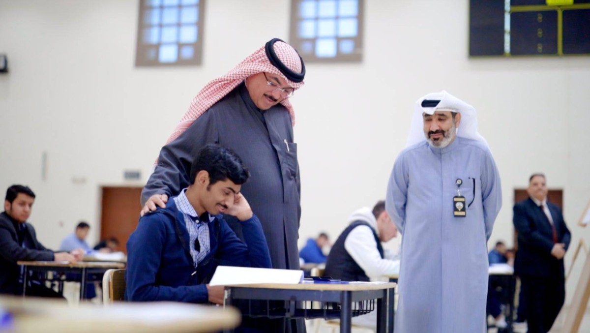 
Minister of Education Jalal Al-Tabtabaei pats a grade 12 student on the back as an exam proctor looks on during the minister’s tour of exam halls. 