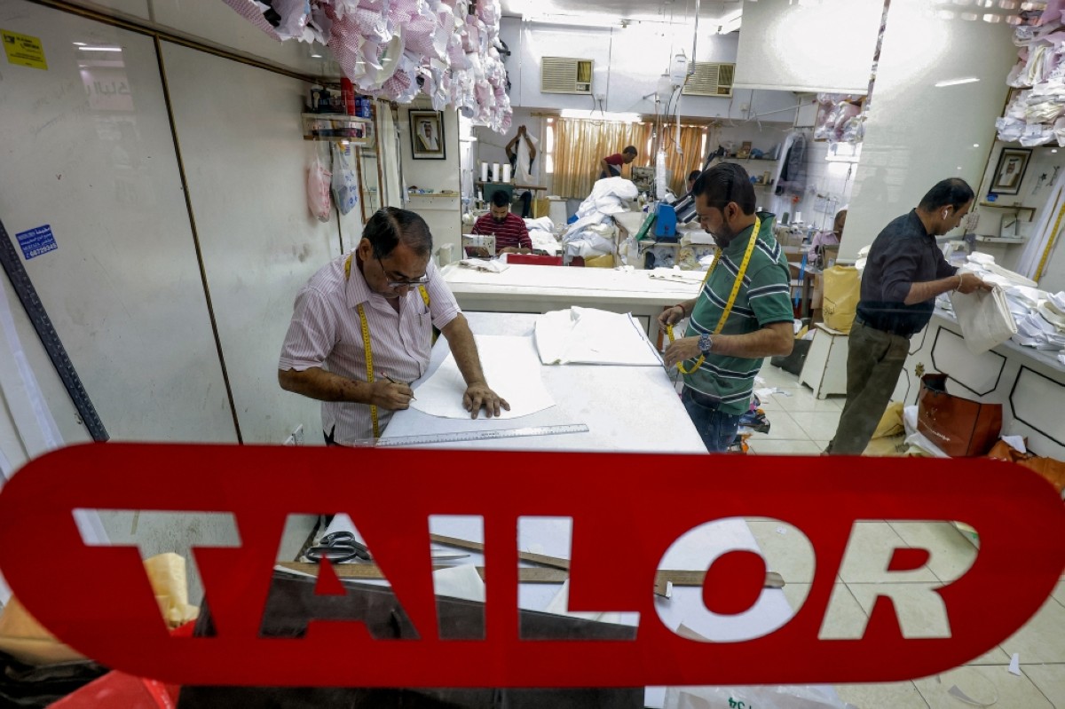 Tailors make dishdashas at a shop in Kuwait City.  -- Photos by Yasser Al-Zayyat