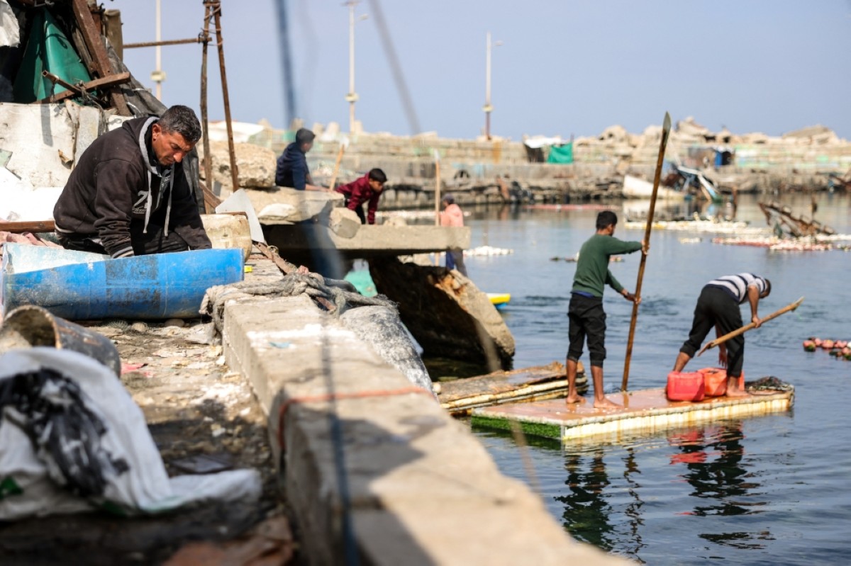 GAZA: A man prepares bait paste as Palestinian men use the door of a refrigerator as a makeshift rowing boat to catch fish at the port of Gaza City on March 9, 2025. — AFP photos 