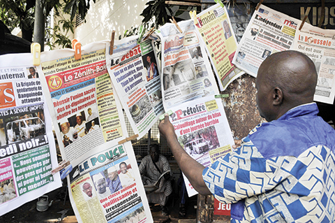 A man reads a newspaper hunging in front of a shop in Bamako on August 10, 2015. A jihadist group is strongly suspected of carrying out the siege on the Hotel Byblos which began early on August 7 and that ended with the deaths of at least 12 people including five UN workers, a security source said on August 9. AFP PHOTO / HABIBOU KOUYATE
