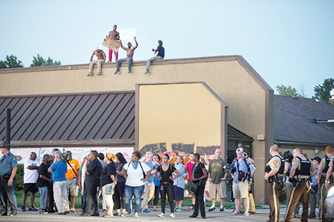 FERGUSON, MO - AUGUST 10: Demonstrators, marking the one-year anniversary of the shooting of Michael Brown, protest along West Florrisant Street on August 10, 2015 in Ferguson, Missouri. Mare than 100 people were arrested today during protests in Ferguson and the St. Louis area. Brown was shot and killed by a Ferguson police officer on August 9, 2014. His death sparked months of sometimes violent protests in Ferguson and drew nationwide focus on police treatment of black offenders.   Scott Olson/Getty Images/AFP == FOR NEWSPAPERS, INTERNET, TELCOS & TELEVISION USE ONLY ==