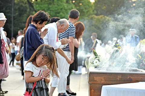 People pray for the victims of the 1945 atomic bombing, at the Peace Memorial Park in Hiroshima on August 6, 2015. Tens of thousands gathered for peace ceremonies in Hiroshima on August 6 on the 70th anniversary of the atomic bombing that helped end World War II, but still divides opinion today over whether the total destruction it caused was justified. AFP PHOTO / KAZUHIRO NOGI