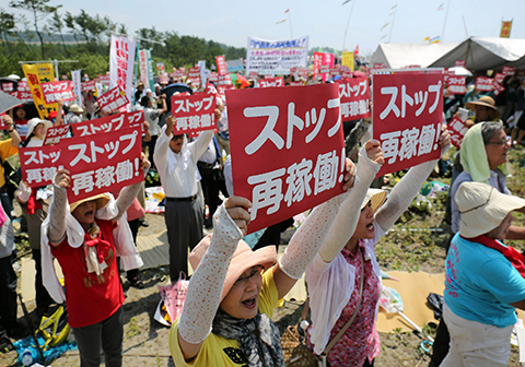 This picture taken on August 9, 2015 shows anti-nuclear protesters holding a rally against the restart of a nuclear reactor in front of the Kyushu Electric Power Sendai nuclear power plant in Satsumasendai, Kagoshima prefecture, on Japan's southern island of Kyushu. Japan is set to restart a mothballed nuclear reactor for the first time in two years on August 11, 2015, the operator said, as anti-atomic sentiment still runs high following the 2011 Fukushima crisis.    JAPAN OUT     AFP PHOTO / JIJI PRESS