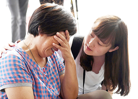 TOPSHOTSnA relative of a passenger on missing Malaysia Airlines MH370, is consoled by a journalist outside the Malaysia Airlines' office in Beijing on August 6, 2015. Chinese relatives of passengers aboard missing flight MH370 expressed anger and disbelief on August 6 after Malaysia's prime minister said wreckage found on a French Indian Ocean island was from the plane. AFP PHOTO / GREG BAKER