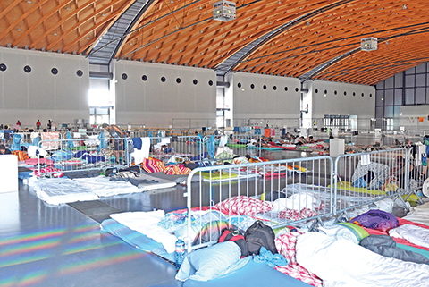 Refugees rest on matressses at a temporary residence for 500 people hosted in a hall at the Fairground of Karlsruhe, western Germany on August 8, 2015. Germany faces a record influx of refugees, with 300,000 asylum seekers registered since January 2015. AFP PHOTO / DPA / ULI DECK +++ GERMANY OUT