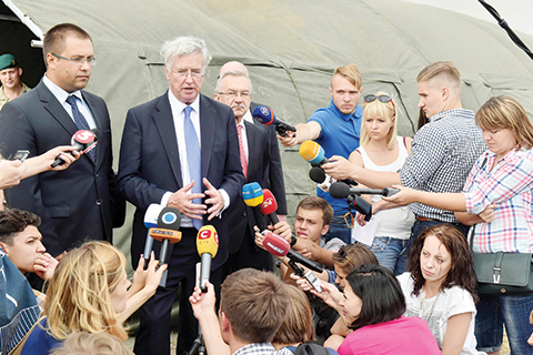 British Defence Secretary Michael Fallon (2L, top) speaks to journalists after military exercises on the shooting range of Ukrainian forces near Ghytomyr, some 150 km west of Kiev, on August 11, 2015. The Defence Secretary announced further enhancements of the UK training programme for Ukrainian armed forces while visiting the country. AFP PHOTO/ SERGEI SUPINSKY
