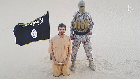 This image made from a militant video posted on a social media website on Wednesday, Aug. 5, 2015, which has been verified and is consistent with other AP reporting, purports to show a militant standing next to another man who identifies himself as 30-year-old Tomislav Salopek, kneeling down as he reads a message at an unknown location. The video purportedly released by the Islamic State group threatens to kill the Croatian hostage if Egyptian authorities do not release 