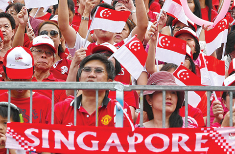 People wave national flags during Singapore's 50th National day anniversary celebration at the Padang in Singapore on August 9, 2015. Singapore celebrated 50 years of independence on August 9 with a grand parade, hailing a remarkable transformation from colonial backwater to regional powerhouse, for the first time without its revered founding leader Kee Kuan Yew. AFP PHOTO / ROSLAN RAHMAN