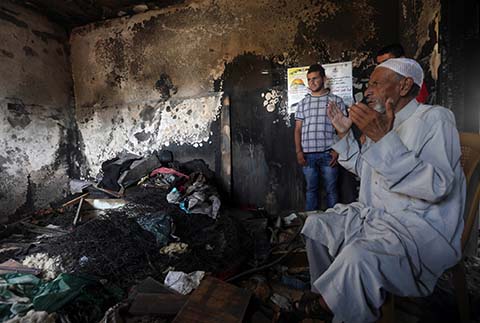 Mohammed, the father of Saad Dawabsha, a Palestinian man who was killed alongside his toddler when their house was firebombed by Jewish extremists on July 31, 2015, prays at the family's burnt-out home in the West Bank village of Duma, the day after his son's funeral on August 9, 2015. Dawabsha died in hospital in the southern Israeli city of Beersheba where he was being treated for third-degree burns for the past eight days. AFP PHOTO / JAAFAR ASHTIEYH