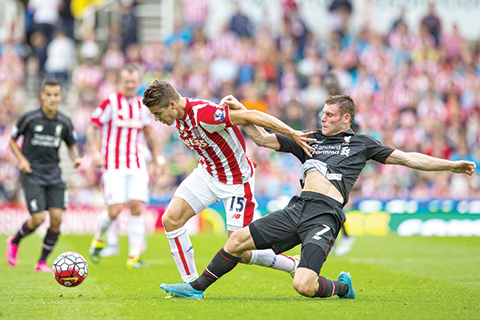 Stoke's Marco van Ginkel, centre, is tackled by Liverpool's James Milner during the English Premier League soccer match between Stoke and Liverpool at the Britannia Stadium, Stoke, England, Sunday Aug. 9, 2015. (AP Photo/Jon Super)