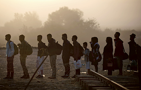 TOPSHOTSnMigrants and refugees queue to cross the Greek-Macedonian border near Gevgelija on September 18, 2015. Land routes to northern Europe from the Balkans were all closed for migrants, after Croatia closed their border with Serbia because of the unprecedented human wave. The crisis, challenging the EU's humanitarian reputation and its vaunted policy of border mobility, has triggered an extraordinary summit, bringing leaders of the 28-nation bloc together next week. AFP PHOTO / NIKOLAY DOYCHINOV