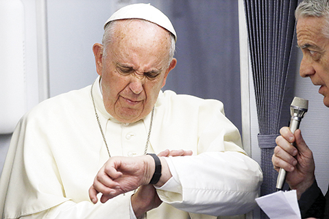 FILE - In this July 12, 2015, file photo, Pope Francis checks his watch as Vatican spokesman Federico Lombardi stands beside him, during an airborne press conference aboard the airplane directed to Rome, at the end of his Apostolic journey in Ecuador, Bolivia and Paraguay. The Pope plans to meet Cuba’s president and its priests, its young and its sick, its churchgoers and its seminarians as he travels across the island starting Saturday.  But not its dissidents. Vatican spokesman Federico Lombardi said that Francis had not accepted any invitations to meet with dissidents, and well-known opposition members told The Associated Press they have received no invitation to see him. (AP Photo/Gregorio Borgia, File)