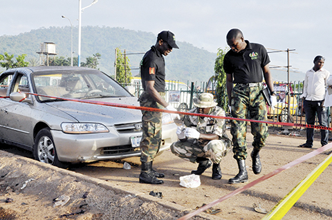 Soldiers gather at the site of a bomb explosion in Abuja, Nigeria, Saturday, Oct. 3, 2015.  Multiple bombs detonated in two locations killing at least 15 people, the National Emergency Management Agency said Saturday, although no group has claimed responsibility the attack has attributes of others by Boko Haram, the home-grown Islamic extremist group.(AP Photo/Gbenga Olamikan)