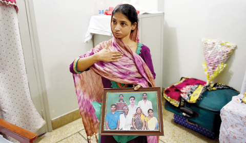 In this photograph taken on October 22, 2015, deaf-mute Indian woman, Geeta holds a photograph of a family in India which she believes is her family, during an interview at the EDHI Foundation. — AFP