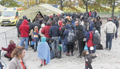 Dozens of migrants wait to be registered after arriving from Croatia. - AP  