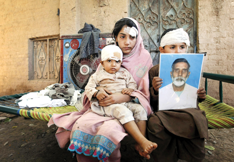 A Pakistani boy holds a photograph of his grandfather killed from an earthquake. — AP