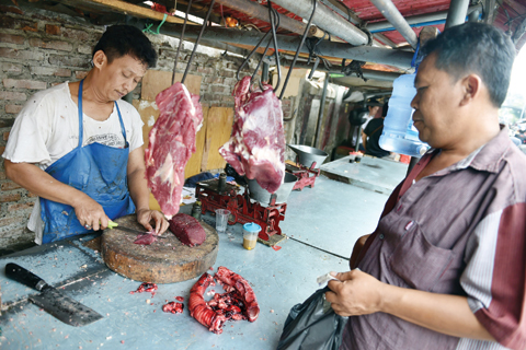 JAKARTA, Indonesia : In this picture taken on November 4, 2015, a butcher (left) prepares meat for a customer at his stall in Jakarta. — AFP photos