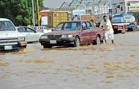JEDDAH: A man pushes his car in floodwaters following heavy rainfall in this Saudi port city yesterday. - AFP 