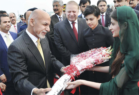 RAWALPINDI: Afghan President Ashraf Ghani (left) receives bouquet from a Pakistani woman as Prime Minister Nawaz Sharif (center) looks on upon his arrival at the military Nur Khan airbase. — AFP photos