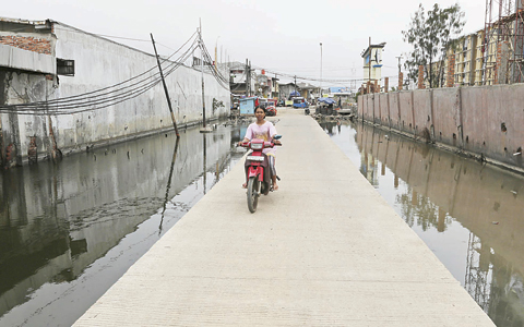 JAKARTA: In this photo, a motorist rides on a bridge built on an area regularly flooded with seawater in Jakarta, Indonesia. —AP