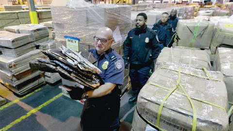 KEARNEY: US Customs and Border Protection officer Jerome Bria, foreground, carries a cache of counterfeit designer bags found in a shipment at H&M Terminals Transport Inc warehouse in Kearney, NJ. Counterfeiting today is a multibillion-dollar business in China, which produces nearly nine of every 10 fake items seized at US borders. —AP