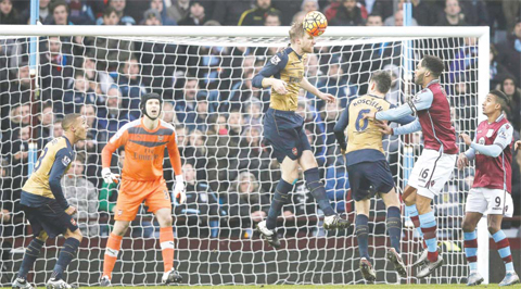BIRMINGHAM: Arsenal’s Czech goalkeeper Petr Cech (2L) watches as Arsenal’s German defender Per Mertesacker jumps to clear the ball during the English Premier League football match between Aston Villa and Arsenal at Villa Park in Birmingham, central England yesterday. Arsenal won the match 2-1. — AFP