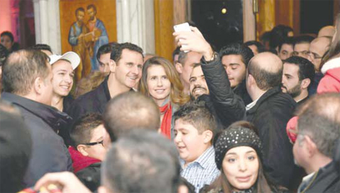 Syrian President Bashar Al-Assad and his wife Asma pose for a picture with a Syrian man as they attend a Christmas choral presentation at the Lady of Damascus Catholic Church in the Syrian capital on Friday. — AFP