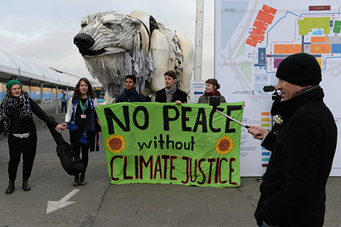 Activists hold a banner reading 'No peace without climate justice' in front of a giant polar beer puppet called Aurora by environmental organization Greenpeace during a demonstration at the venue of the COP21 United Nations climate change conference in Le Bourget, on the outskirts of Paris, on December 11, 2015. The COP21 was supposed to finish on December 11, but the final deal of the 195-nation conference on global warming was extended another day after ministers failed to bridge deep divides during a second consecutive all-night round of negotiations. / AFP / MIGUEL MEDINA