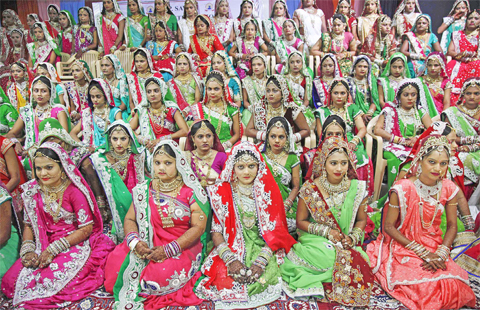 Indian brides sit for a group photo before a mass wedding hosted by a diamond trader in Surat, India, yesterday. 151 young couples tied the knot at the mass wedding hosted by Indian diamond trader Mahesh Savani, who has been funding the weddings of fatherless women in the city of Surat for several years. Weddings in India are expensive affairs with the bride’s family traditionally expected to pay the groom a large dowry of cash and gifts. Hundreds of people, mostly family members and neighbors of the couple, are hosted at lavish meals over a number of days adding to the costs. — AP photos