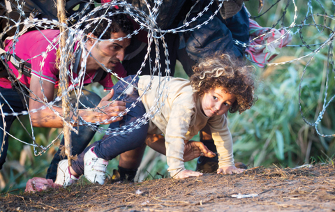 ROSZKE: In this Thursday, Aug 27, 2015 photo, a child is helped cross from Serbia to Hungary through the barbed wire fence. -- AP n