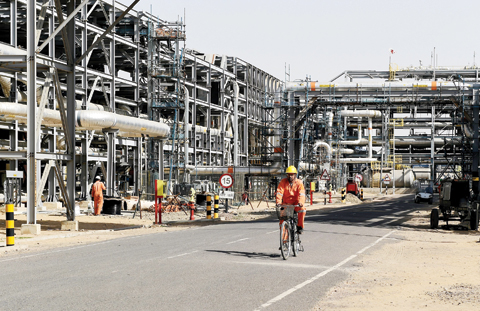 BARMER, India: In this photograph taken on Dec 11, 2015, a worker cycles by machinery at a Cairn India oil and gas exploration plant in Rajasthan. — AFP