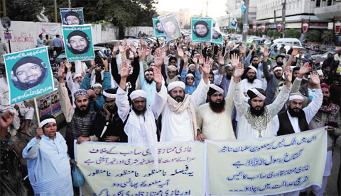 KARACHI: Pakistani supporters of former police bodyguard Mumtaz Qadri carry placards with his portrait as they shout slogans during a protest yesterday. — AFP