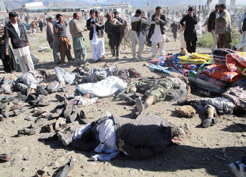 KURRAM: Pakistani men gather beside the bodies of victims of a bomb explosion at a market in Parachinar, the capital of Kurram tribal district. — AFP