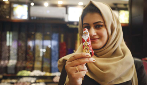 GAZA CITY: A Palestinian Muslim woman poses for a photo holding a chocolate bearing an image of Santa Claus at a shop. — AFP