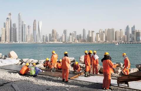DUBAI: In this Sept 22, 2015 photo, with the Marina Waterfront skyline in the background, laborers work at a construction site at the Palm Jumeirah. — AP
