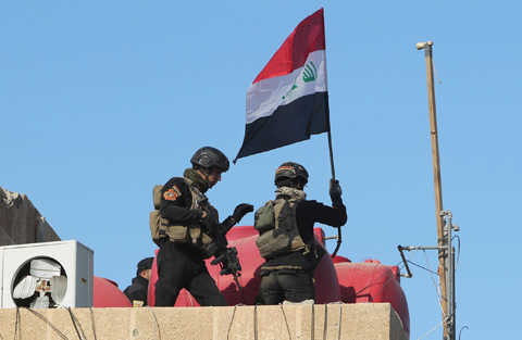RAMADI: Members of Iraq's elite counter-terrorism service place the national flag yesterday on the roof of a building of the government complex after they recaptured this city. -AFP 
