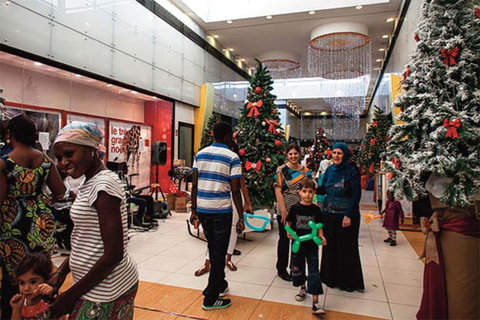 People walk past Christmas trees at a shopping mall in Darkar, Senegal