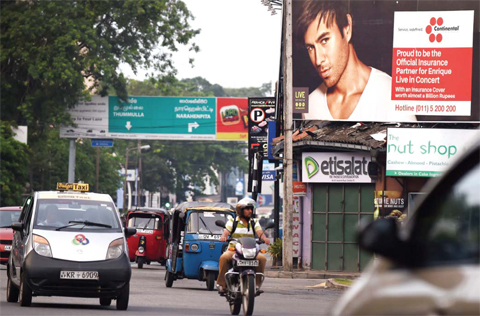 Sri Lankan commuters journey past a billboard in Colombo yesterday, associated with a concert of the Latin pop star Enrique Iglesias. — AFP