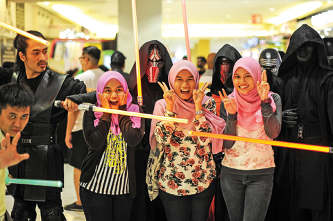 Malaysian Muslim women pose for pictures with members of Malaysia’s Star Wars Fan Club dressed as various characters before watching ‘Star Wars: The Force Awakens’ at a cinema in Subang, outside Kuala Lumpur yesterday. — AP/AFP photos