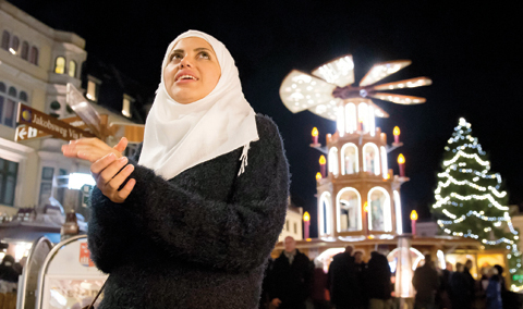 ZWIKAU: In this Dec 8, 2015 file picture Syrian refugee Reem Habashieh stands in front of a traditional wooden Christmas pyramid at the Christmas market. - AP photos 