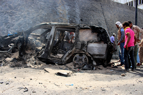Yemenis inspect the scene of a car bomb attack that killed the Governor of Aden Jaafar Saad