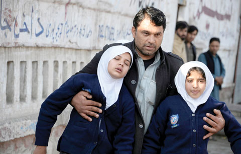 JALALABAD: An Afghan man assists two schoolgirls in the vicinity of an attack from a building close to the Pakistan consulate. — AFP