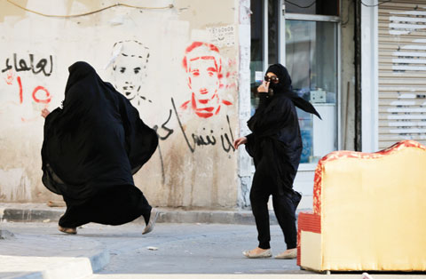 DAIH: Bahraini women run from approaching riot police who were chasing protesters against Saudi Arabia’s execution of Shiite cleric Sheikh Nimr Al-Nimr in Daih, Bahrain, a largely Shiite suburb of the capital. Graffiti on the wall reads, “we will not forget you,” beneath pictures of people killed in previous unrest. — AP