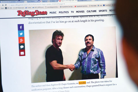 MEXICO CITY: A man reads an article about drug lord Joaquin Guzman, aka “El Chapo”, showing a picture of him (right) and US actor Sean Penn on the website of Rolling Stone magazine yesterday. – AFP 