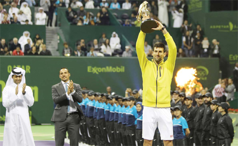 Novak Djokovic of Serbia celebrates with his winning trophy after beating Rafael Nadal of Spain in the final of the Qatar Open tennis tournament