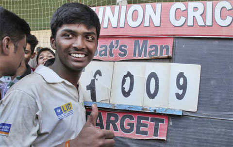 MUMBAI: Pranav Dhanawade, a 15-year-old opening batsman, who scored 1009 not out in a tournament recognized by the Mumbai Cricket Association shows a thumbs up gesture as he poses near the score board in Mumbai, India, yesterday. The Mumbai teenager has become the first batsman to score 1000 runs in an officially recognized innings. — AP